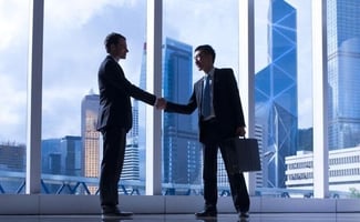 two businessmen shaking each other's hand in an office building